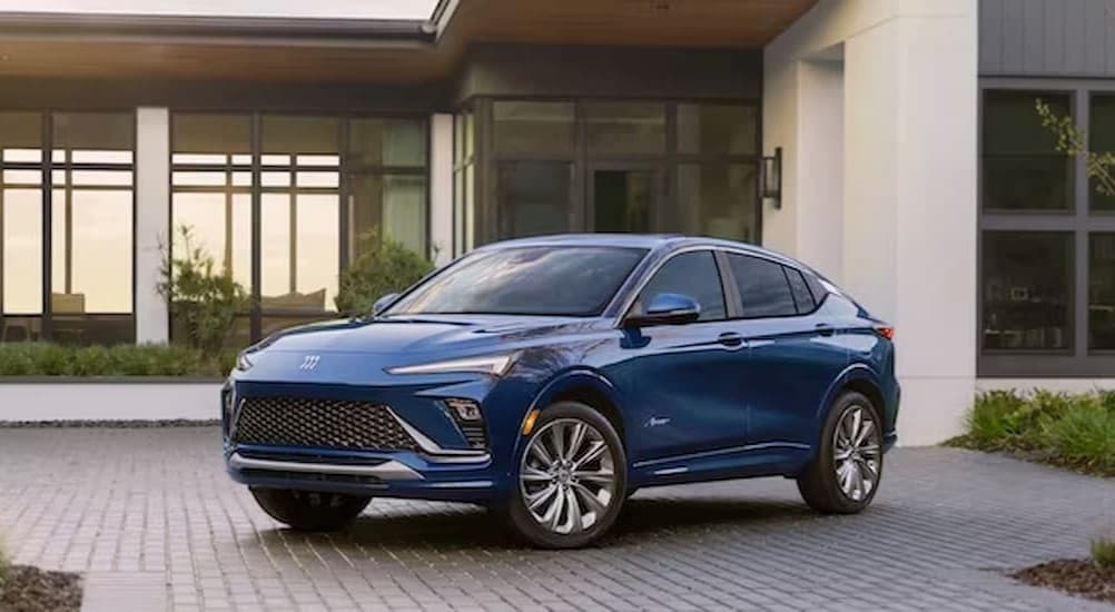 A blue 2024 Buick Envista Avenir parked near a house.