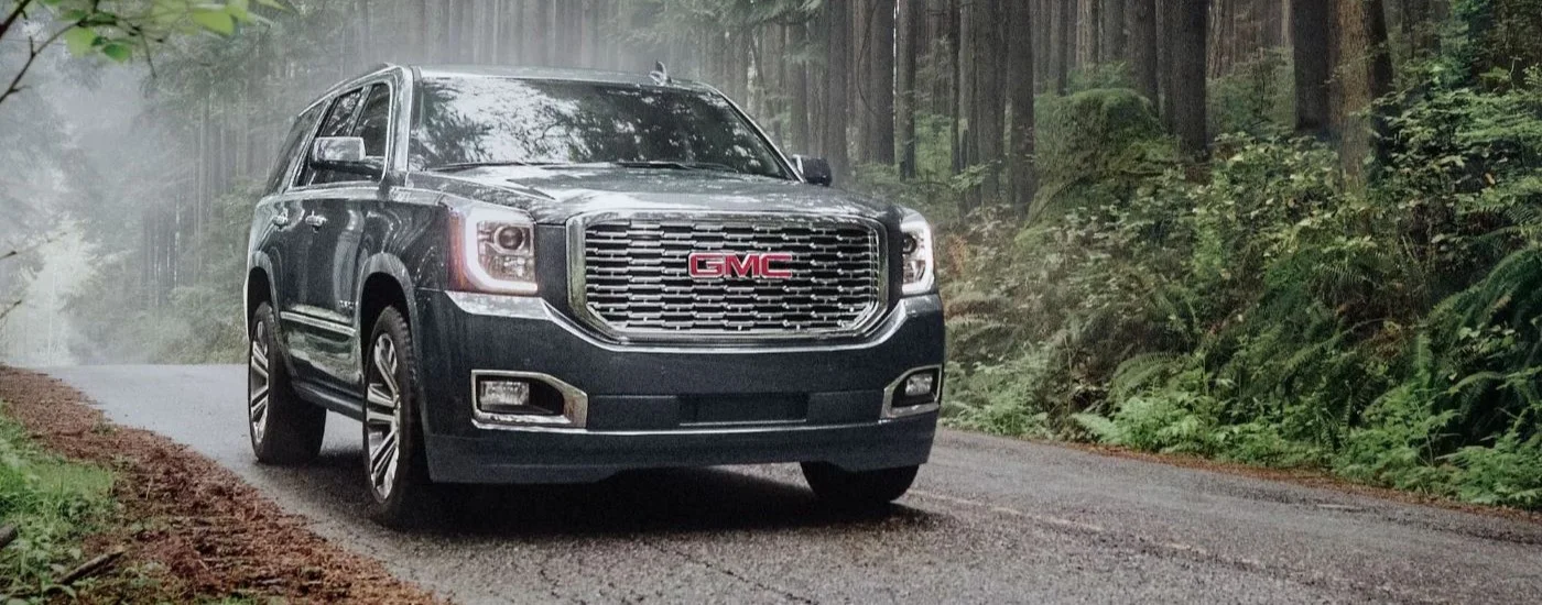 Black 2020 GMC Yukon Denali driving down a road.