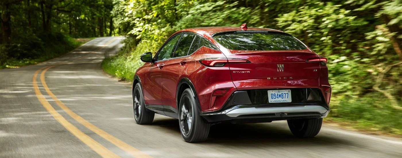 Rear of a red 2025 Buick Envista ST driving down an open road.