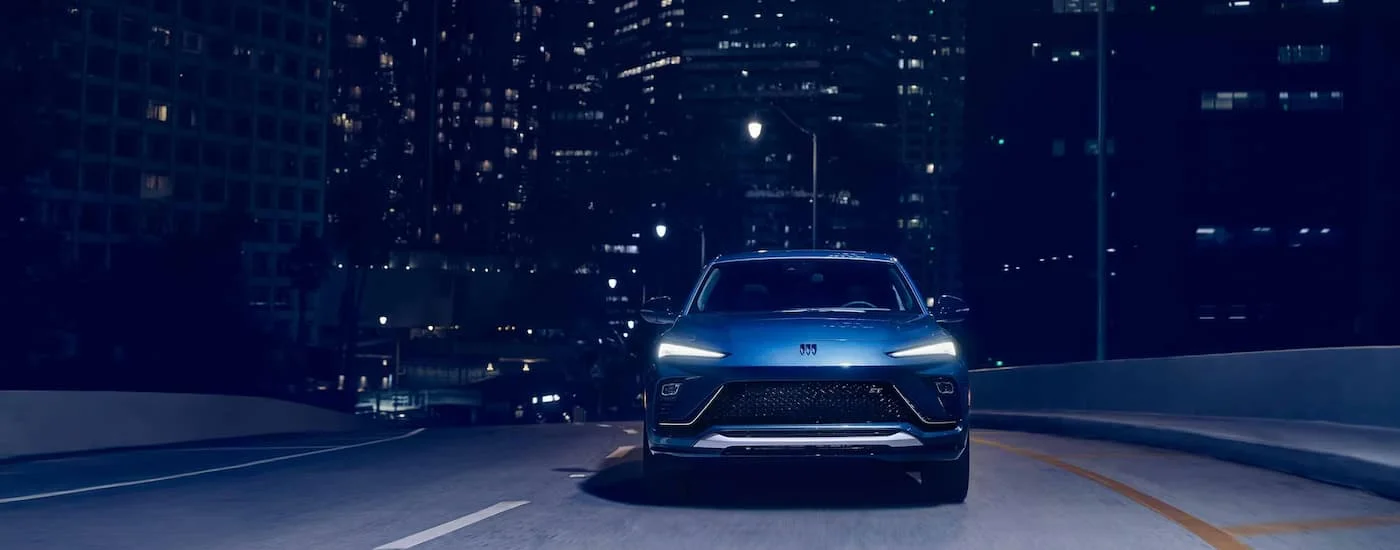 Rear of a blue 2026 Buick Envista driving down a city street.