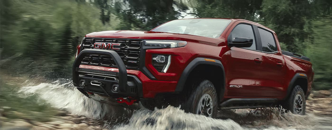 Red 2026 GMC Canyon driving through a river