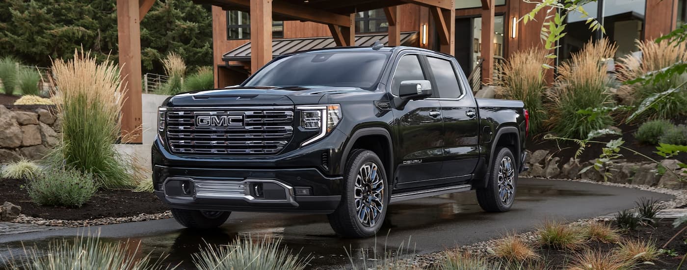 Black 2026 GMC Sierra 1500 parked on a driveway in front of a building.
