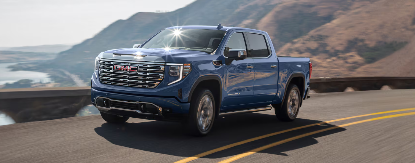 Blue 2026 GMC Sierra 1500 Denali driving past along a coast