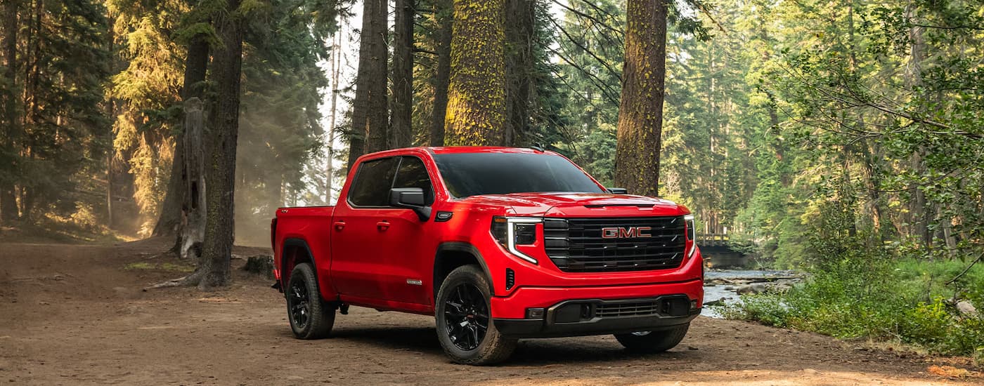 Red 2026 GMC Sierra 1500 parked on dirt in a forest