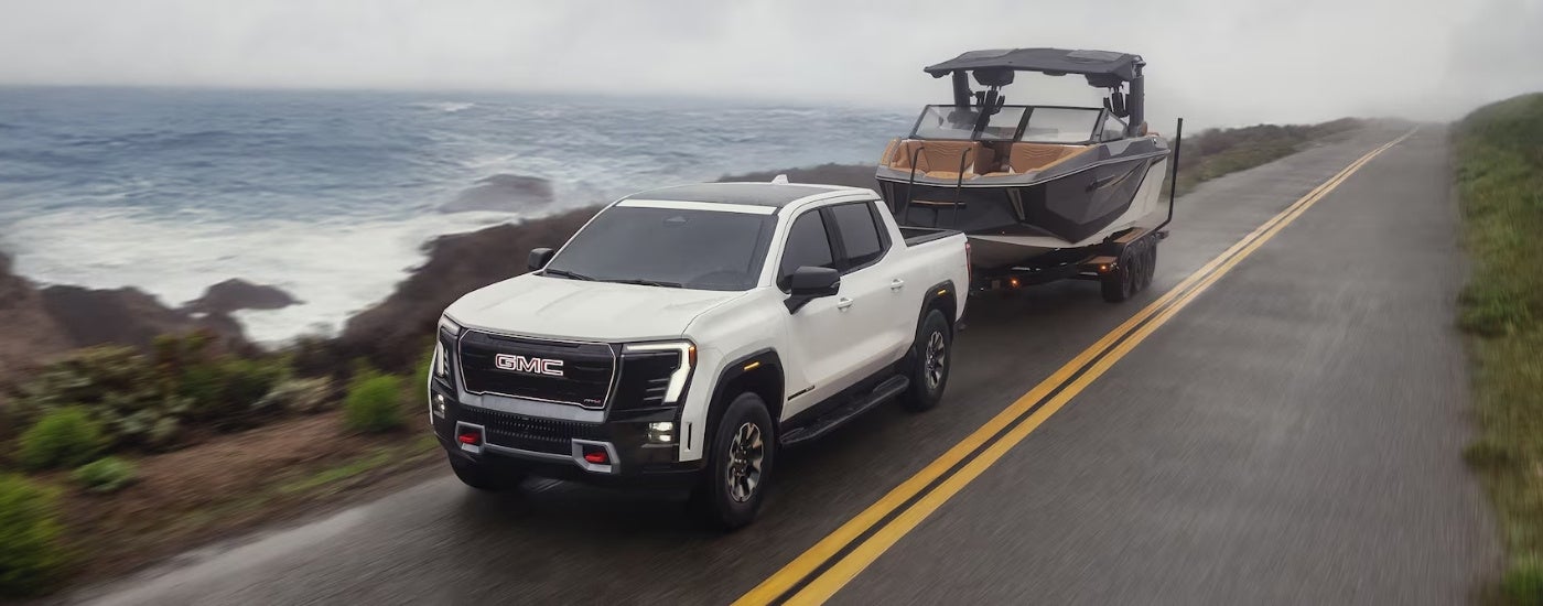 White 2026 GMC Sierra EV AT4 towing a boat