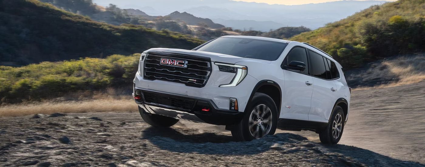 White 2026 GMC Acadia AT4 driving off-road.