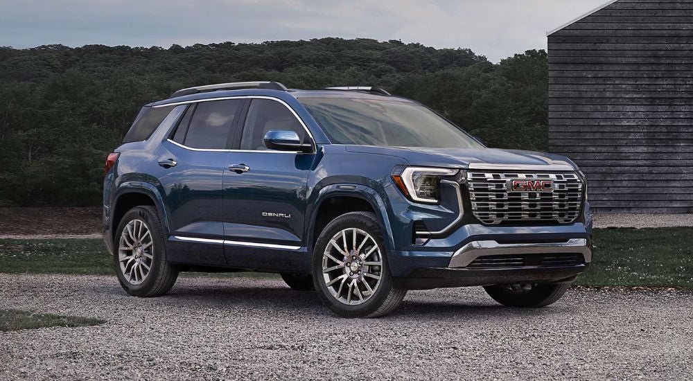 Blue 2027 GMC Terrain Denali parked in front of a barn.