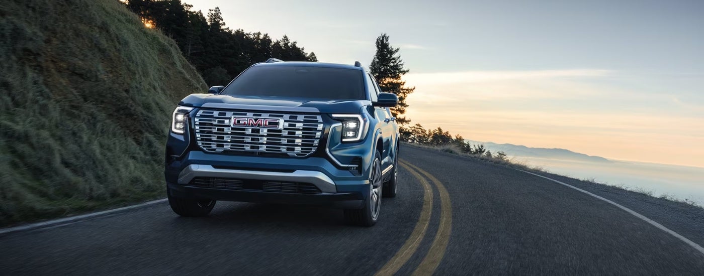 A blue 2026 GMC Terrain driving a mountain road.