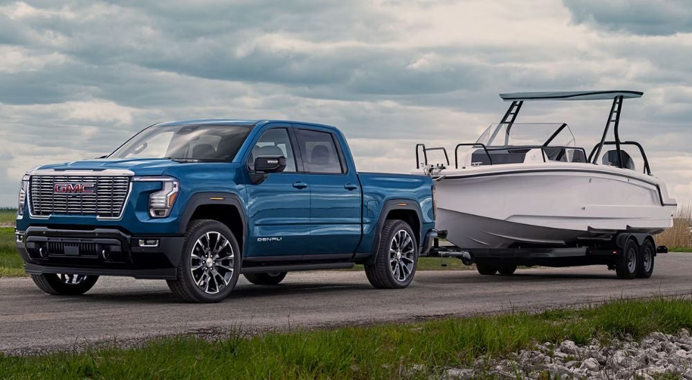 A blue 2027 GMC Sierra 1500 Denali towing a boat.