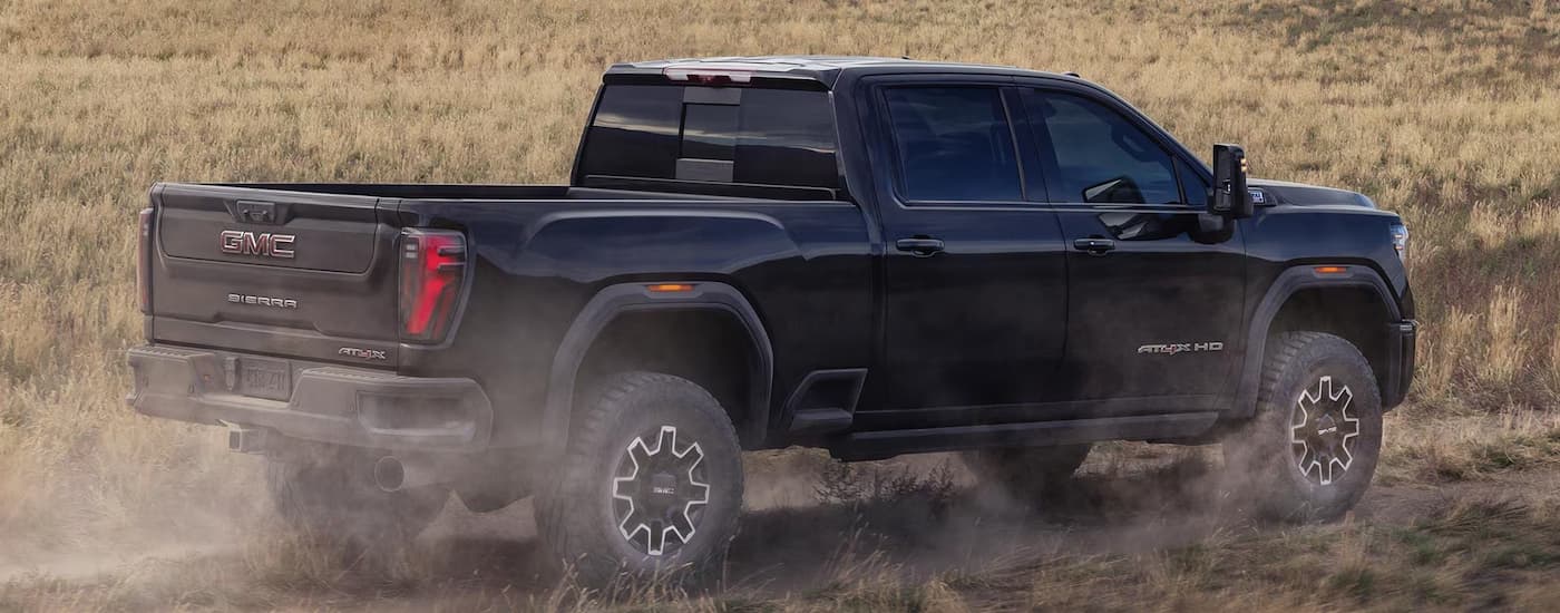 Black 2026 GMC Sierra 2500 HD driving through dirt.