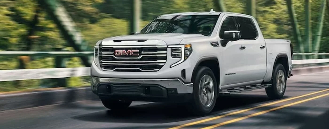 A white 2024 GMC Sierra 1500 for sale in Lighthouse Point driving on a highway.