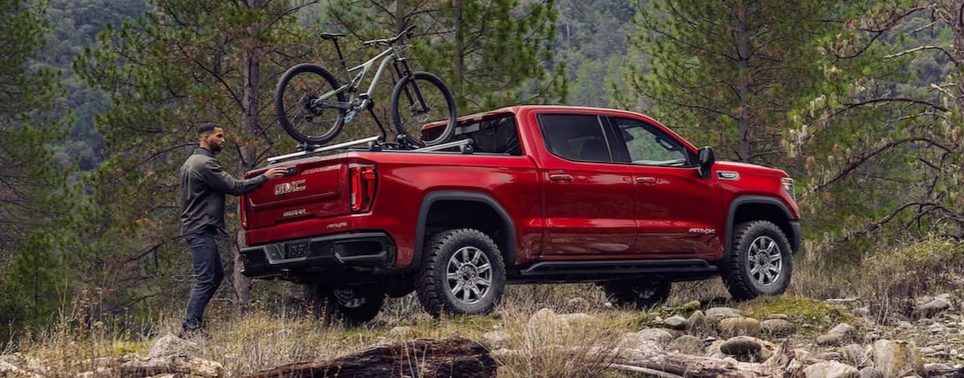 A red 2025 GMC Sierra 1500 AT4X parked off-road.